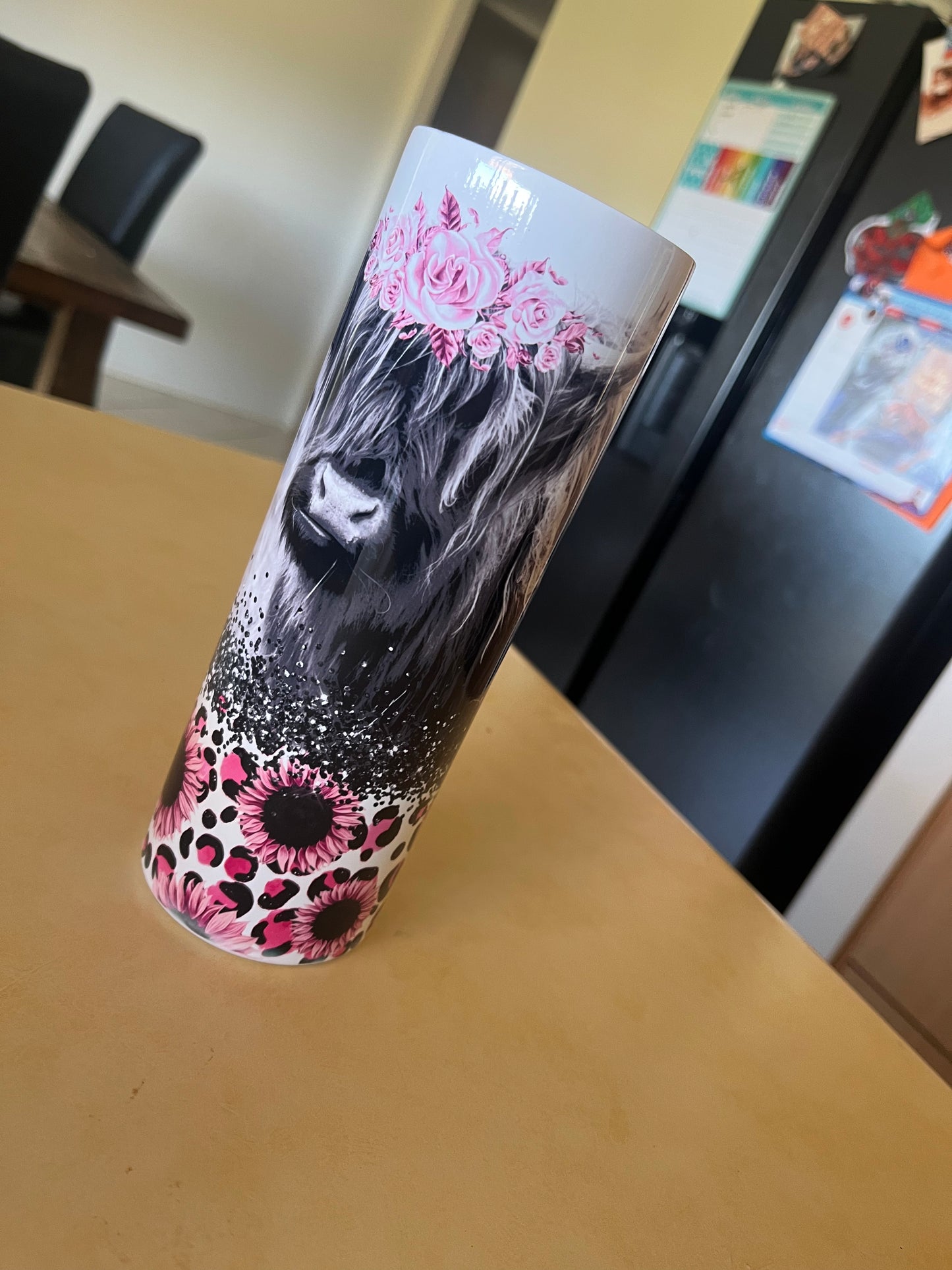 Black and white highland cow with pink flowers